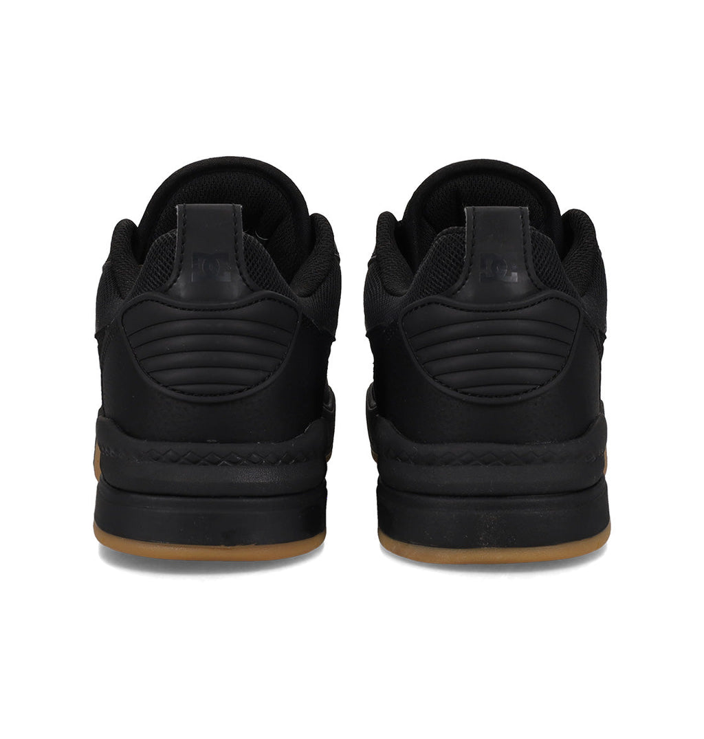 A pair of black DC Shoes Men’s Ascend Skate Shoes viewed from the back, featuring thick soles with a light brown gum base, quilted heel detailing, and black laces—these sneakers seamlessly blend modern comfort with timeless style.