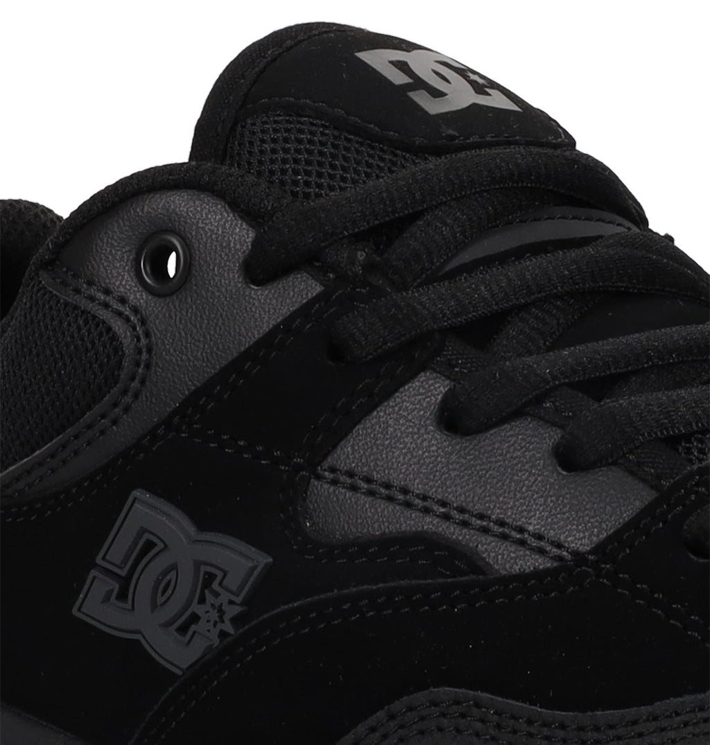 Close-up of a black DC Shoes Men’s Ascend Skate Shoe featuring the side DC logo, laces, and a glimpse of the padded tongue with branded detailing. The shoe combines leather, suede, and mesh textures for a blend of modern comfort and classic skate sneaker style.