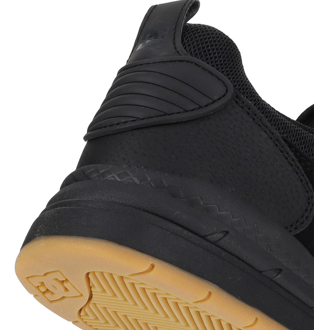 Close-up of the heel and sole of a Men’s Ascend Skate Shoe by DC Shoes, featuring a black upper, rubber gum sole, and textured details that highlight its tread pattern and stitching—a perfect fusion of modern comfort with classic sneaker style.