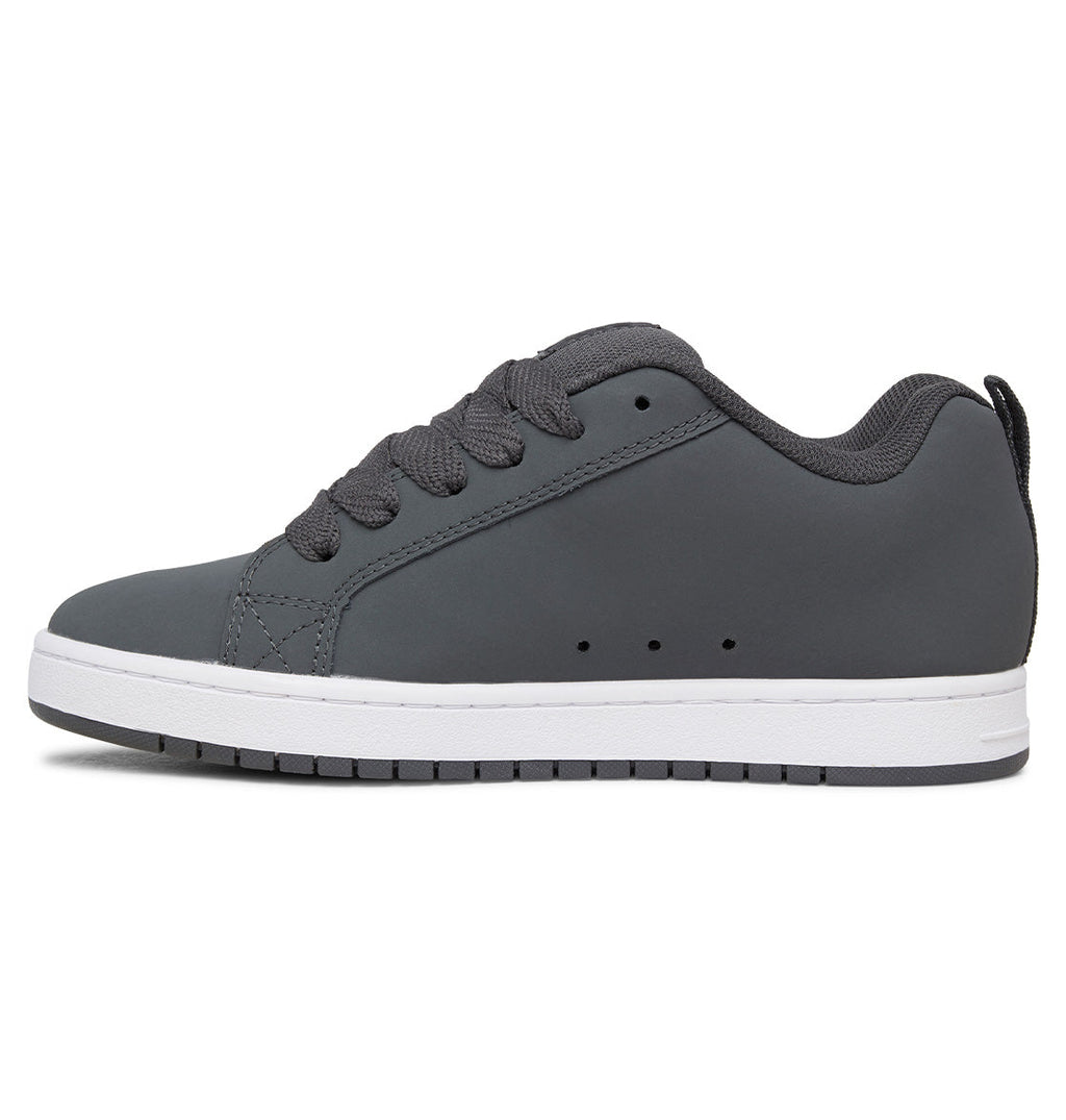 A side view of the Men’s Court Graffik Shoes by DC Shoes is shown against a white background, featuring a gray low-top design with a puffy silhouette, matching laces, subtle stitching details, and a white rubber sole. The iconic DC logo nods to its classic Court Graffik heritage.