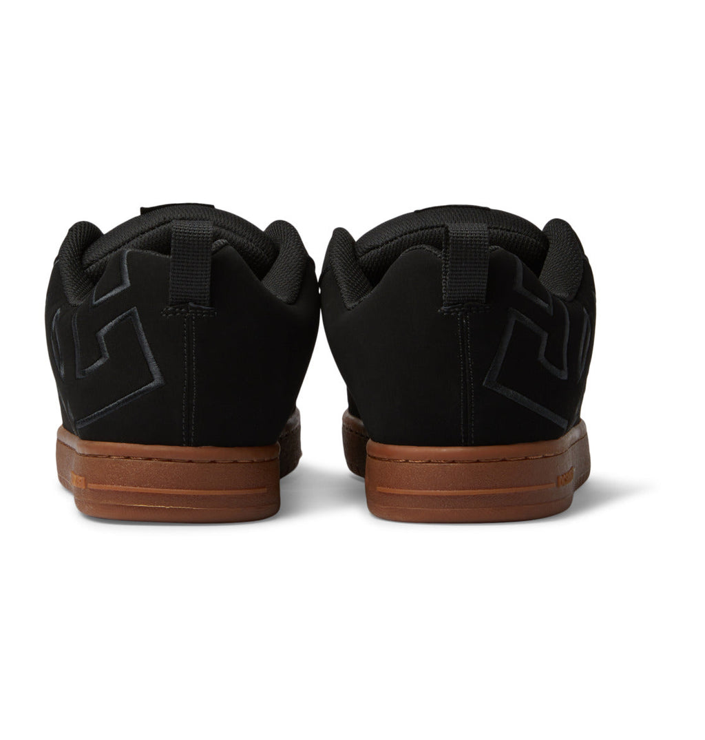 A pair of DC Shoes Men’s Court Graffik skate shoes in black with brown soles, displayed from the back, highlight a stylized E logo on each heel and showcase the classic puffy silhouette.
