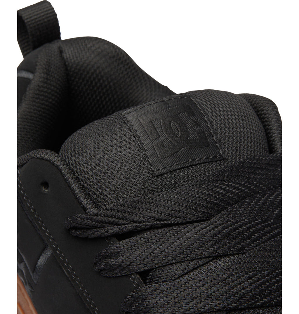 Close-up of a black DC Shoes Men’s Court Graffik Shoe, highlighting the textured tongue with the bold DC Shoes logo, black laces, and a portion of the signature puffy silhouette upper.