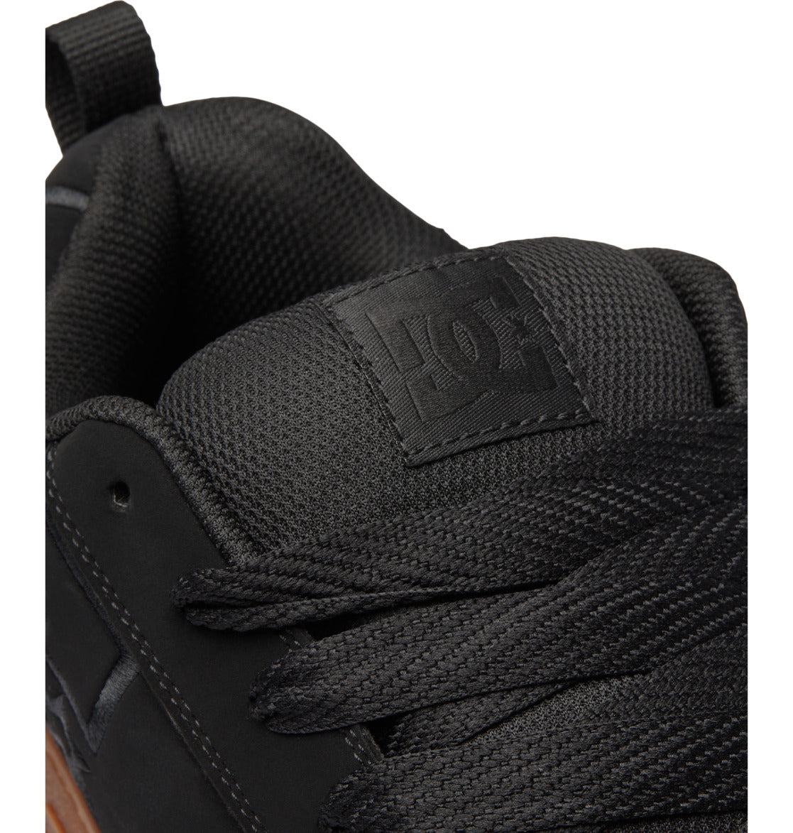 Close-up of a black DC Shoes Men’s Court Graffik Shoe, highlighting the textured tongue with the bold DC Shoes logo, black laces, and a portion of the signature puffy silhouette upper.