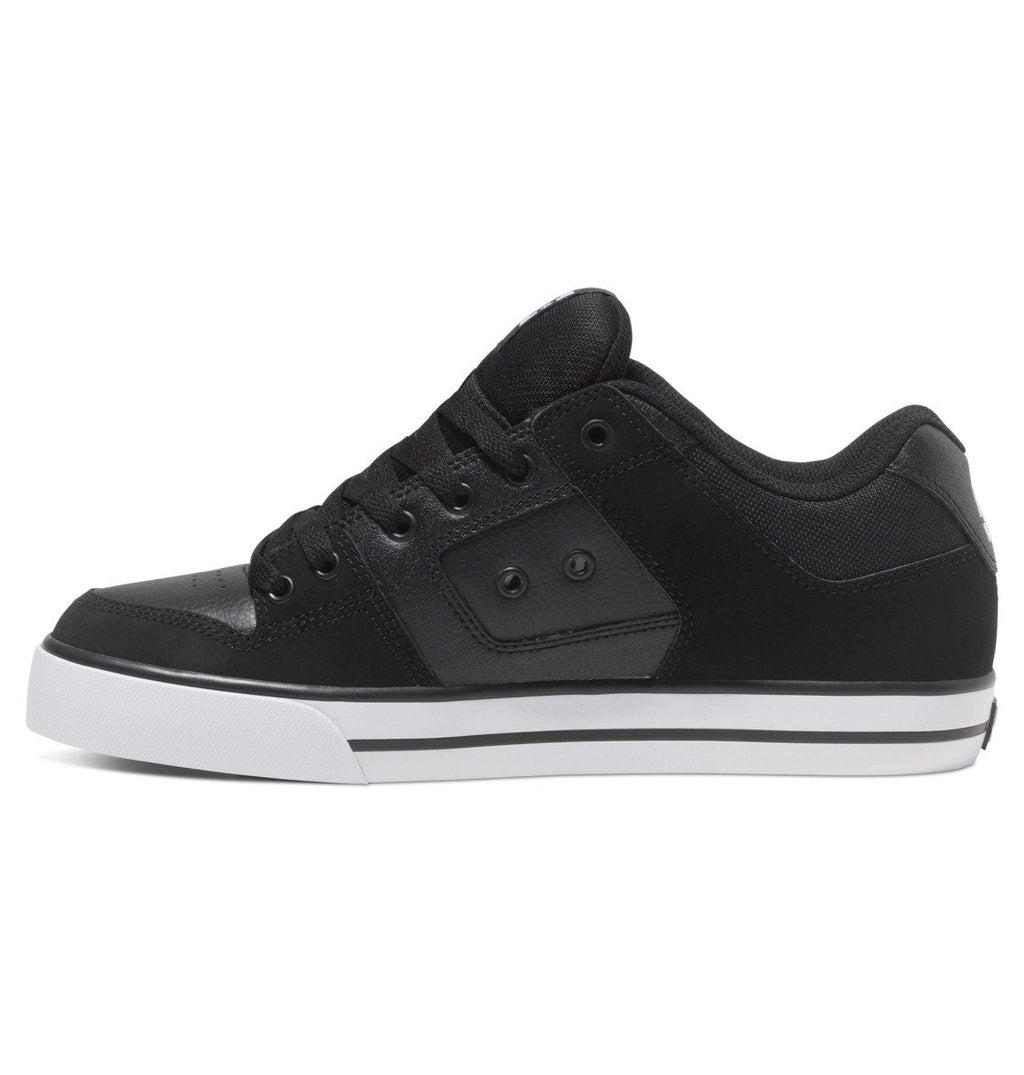 A side view of the DC Shoes Men’s Pure Shoes in black, featuring a white sole, black laces, subtle stitching details, and metal eyelets. This versatile sneaker is ideal for both casual and smart-casual men’s outfits.