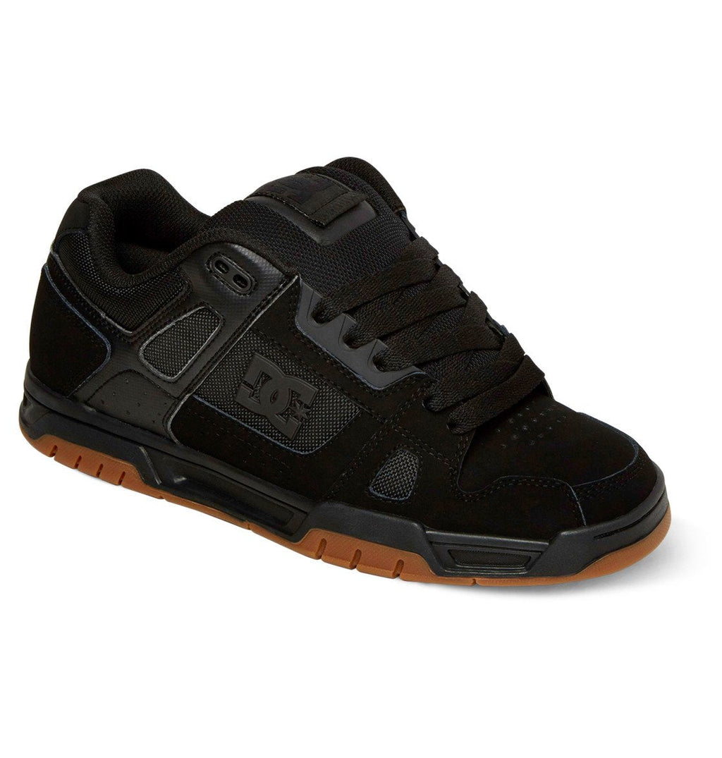 The DC Shoes Men’s Stag Shoes are black low-profile skate shoes featuring black laces, mesh and suede accents, and a brown rubber cupsole for durability. The classic DC logo is displayed on the side, reflecting the timeless style of DC Shoes.