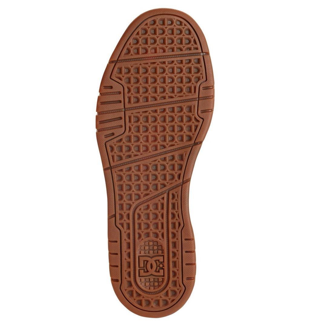 The Men’s Stag Shoes by DC Shoes feature a brown rubber sole with a textured, patterned tread showcasing the DC Shoes logo near the heel. The design incorporates geometric shapes and grooves for superior grip, while the durable cupsole construction—typical of DC Shoes—offers enhanced support.