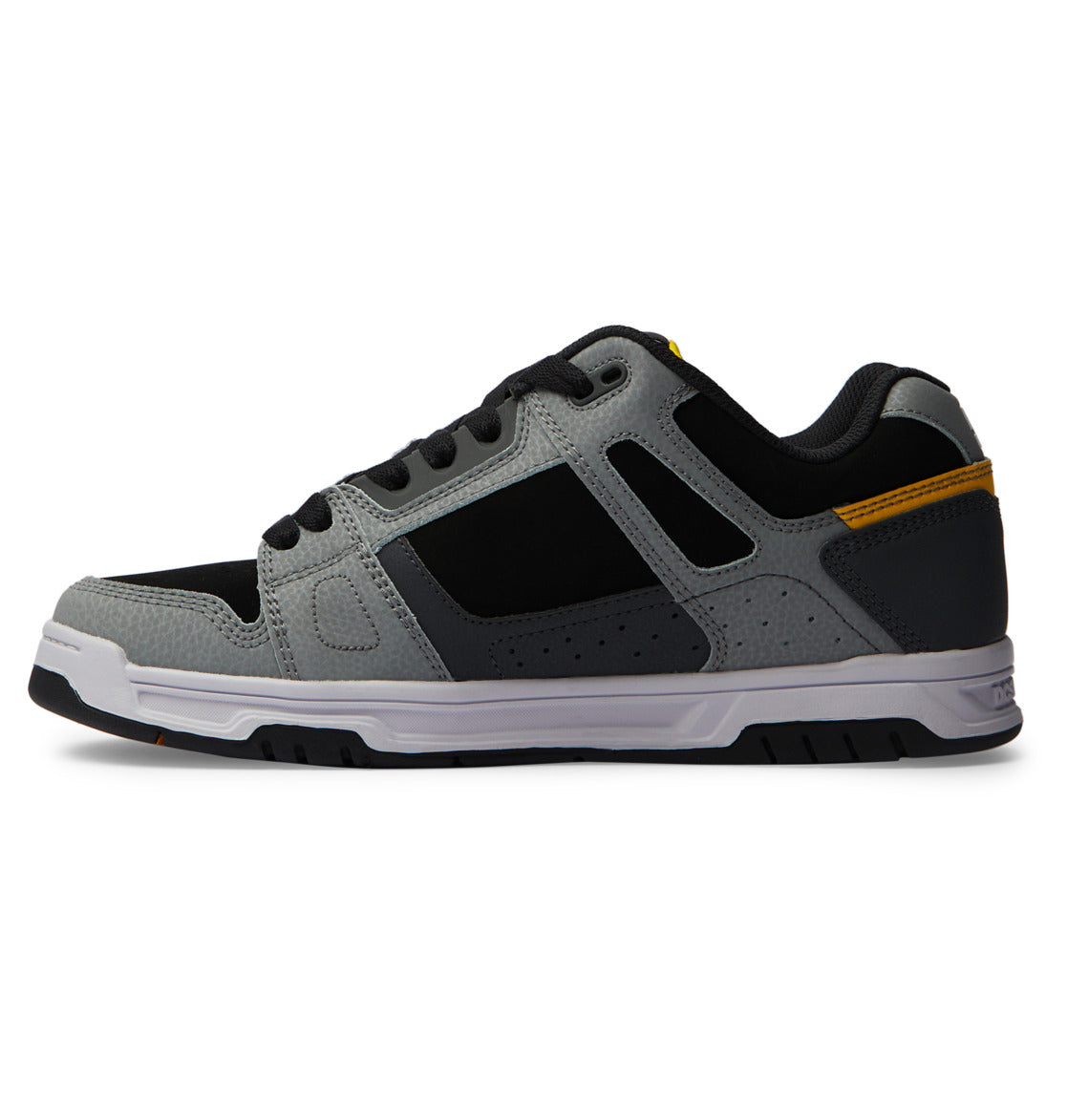The Men’s Stag Shoes by DC Shoes are athletic sneakers in gray and black, featuring a white sole with a sturdy cupsole, subtle yellow accents, and are displayed in a side view against a white background.