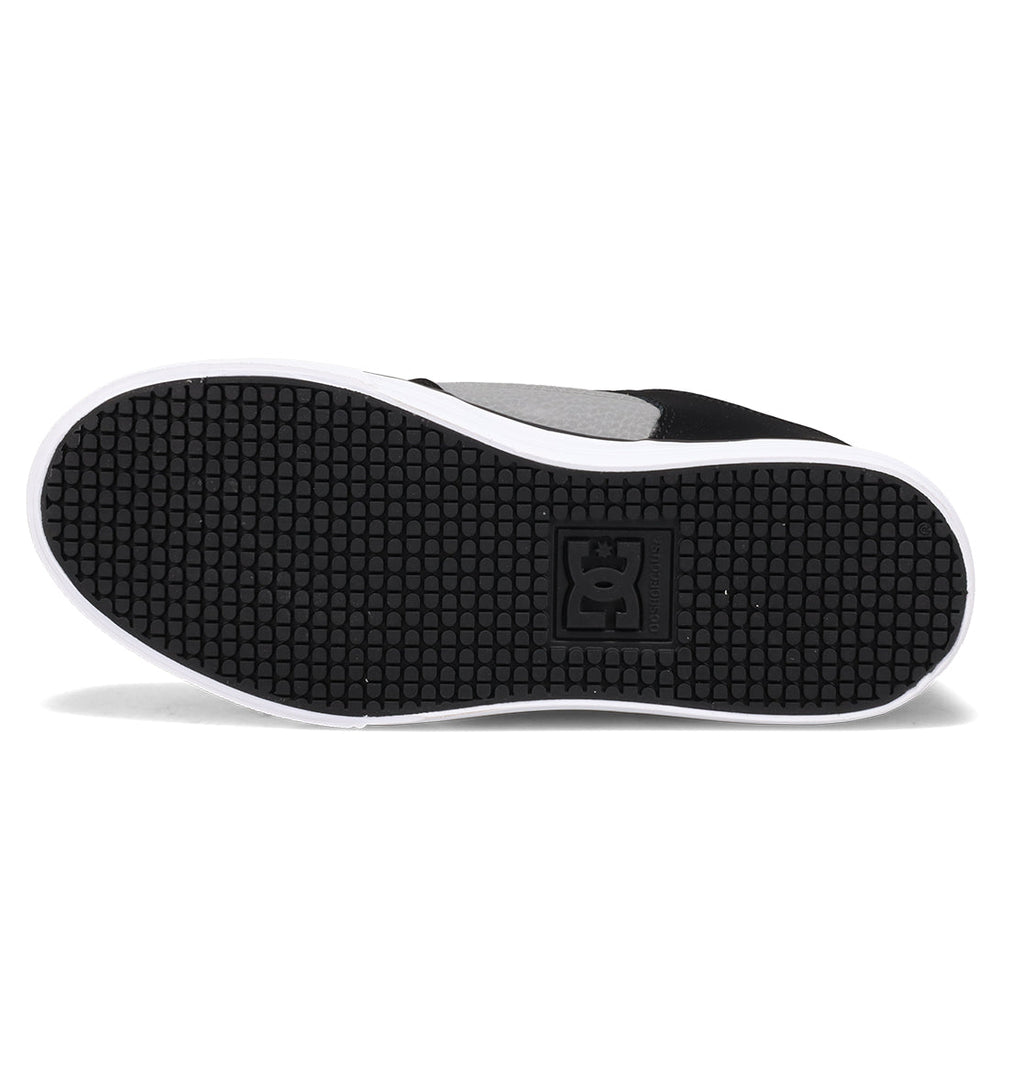 The image shows the sole of the DC Shoes Kids’ Pure Shoe in black and white, featuring a textured grip pattern and a square DC logo near the center, highlighting its durable design.