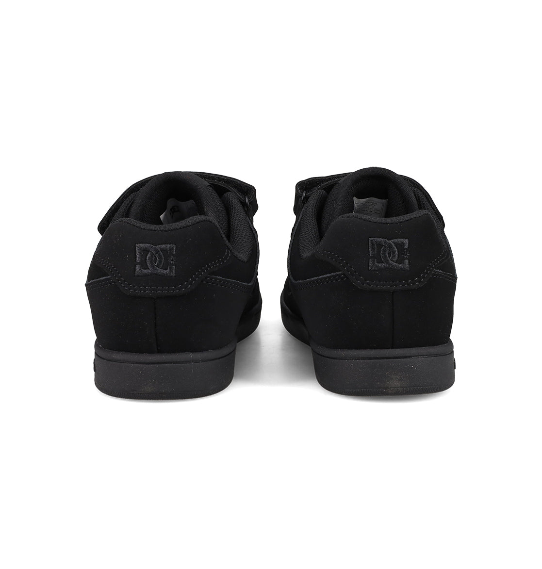 A pair of Kids’ Manteca 4 V Shoes by DC Shoes in black, seen from the back to showcase the heels and signature logo on each shoe. Made with durable suede, these kid-friendly sneakers are positioned side by side on a white background.