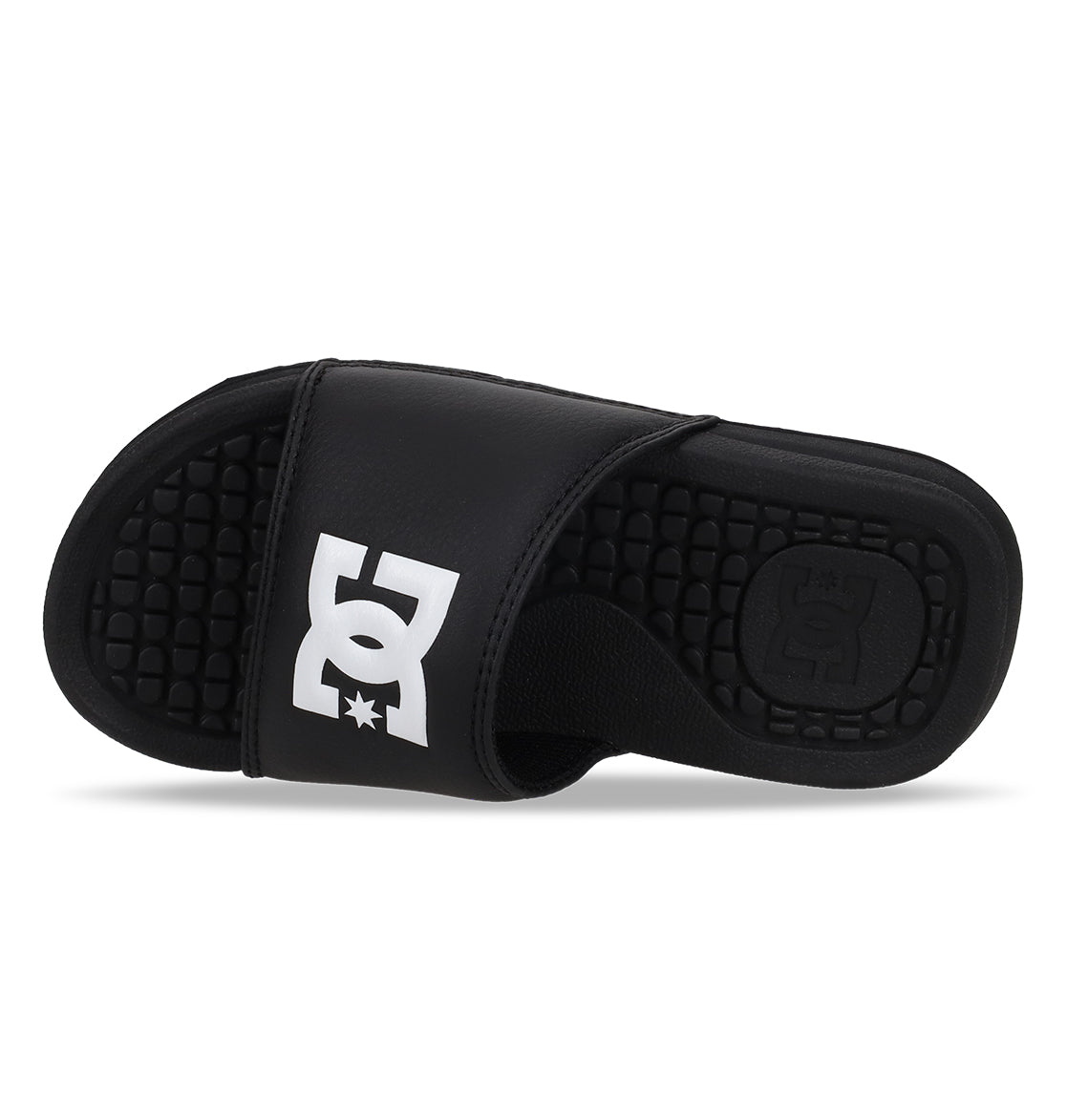 The Kids' Bolsa Slides by DC Shoes are black with a thick strap featuring a bold white logo and a textured footbed for comfort. Positioned on their side, these comfy sandals display both the top and inner sole.