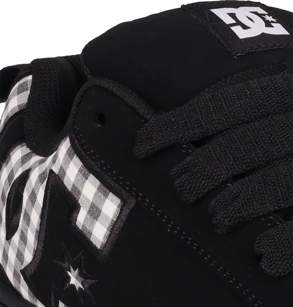 Close-up of the Men's Court Graffik Shoes by DC Shoes: black sneakers with black laces, a white and black checkered pattern, DC logos on the side and tongue, and the signature puffy silhouette.
