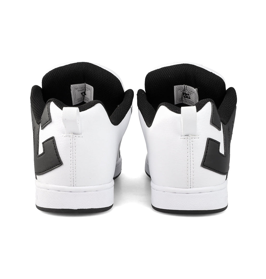 A pair of Women’s Court Graffik Shoes by DC Shoes, featuring black interiors and bold black side designs in a chunky ’90s style, shown from the back.