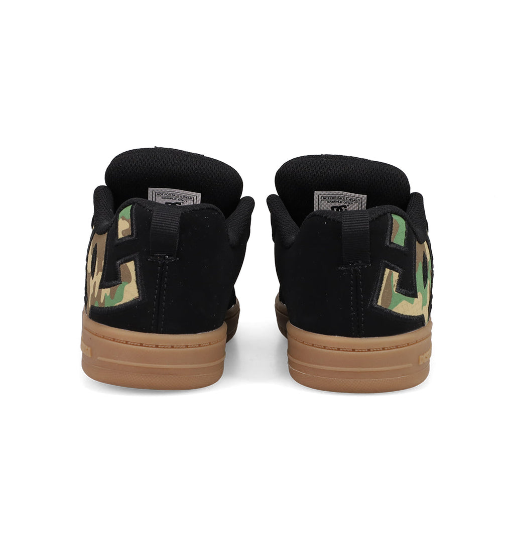 A pair of black Kids' Court Graffik Shoes by DC Shoes with brown soles, large DC logo branding in green camo on the heels, and a puffy low-top silhouette, shown from the back.