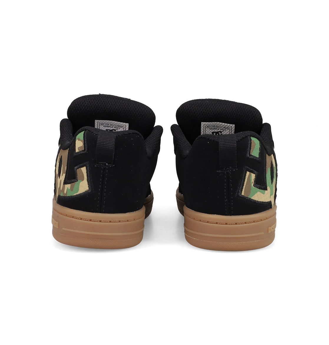 A pair of black Kids' Court Graffik Shoes by DC Shoes with brown soles, large DC logo branding in green camo on the heels, and a puffy low-top silhouette, shown from the back.