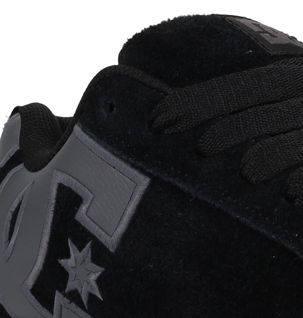 Close-up of the Men’s Court Graffik Special Edition Shoes by DC Shoes—a black sneaker featuring thick black laces and a gray embroidered star logo on the side, accented by its puffy silhouette and distinctive two-tone sole.