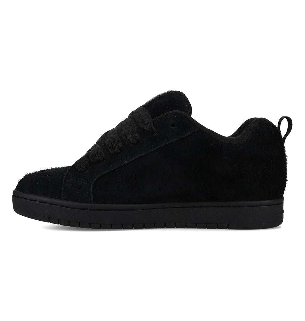 The Men’s Court Graffik Special Edition Shoes by DC Shoes are shown in a left side profile on a white background. This black suede sneaker features a flat, two-tone sole, black laces, and a pull tab at the heel. Designed with a sleek yet subtly puffy silhouette, these men’s shoes offer modern appeal.