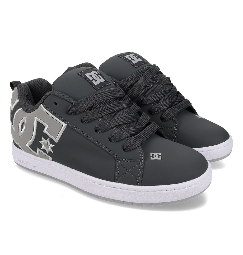 A pair of Men’s Court Graffik Special Edition Shoes by DC Shoes in a dark gray colorway, featuring a puffy silhouette, prominent white DC logos on the sides, black laces, and white rubber soles. The shoes are positioned side by side and angled slightly to the right.