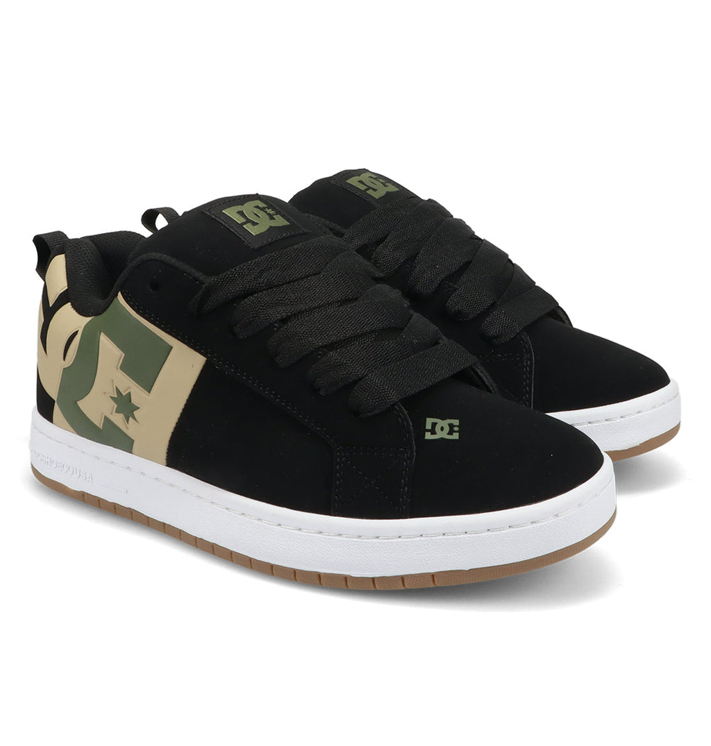 A pair of DC Shoes Men’s Court Graffik Special Edition skate shoes in black, showcasing a classic puffy silhouette with thick black laces, white soles, and distinctive tan and green DC logo accents on the sides and heel, displayed against a white background.