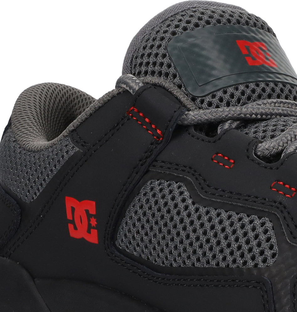 Close-up of the DC Shoes Men’s Metric Shoes in sleek black, grey, and red, featuring striking red stitching, a bold red DC Shoes logo on the side, breathable mesh fabric, and sturdy laces.