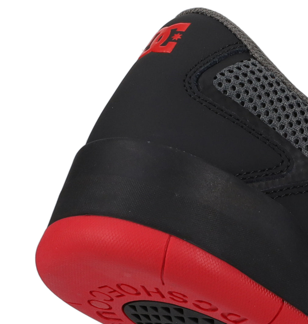 A close-up of the heel of the Men’s Metric Shoes by DC Shoes showcases a black upper, red outsole, grey mesh detailing, and a bold red DC Shoes logo on the heel. This striking pair is a modern example of men’s black, grey, and red shoes from DC Shoes.