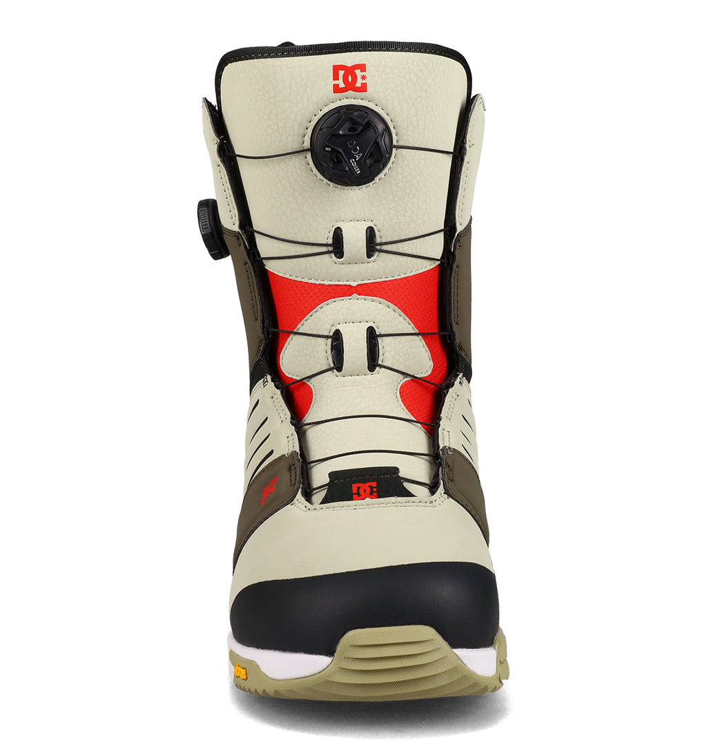 Front view of the DC Shoes Men’s Judge Snowboard Boot in beige and black with red accents, featuring a round black BOA® tightening dial on the tongue and DC logos near the top and toe. The light brown and white sole completes the design.