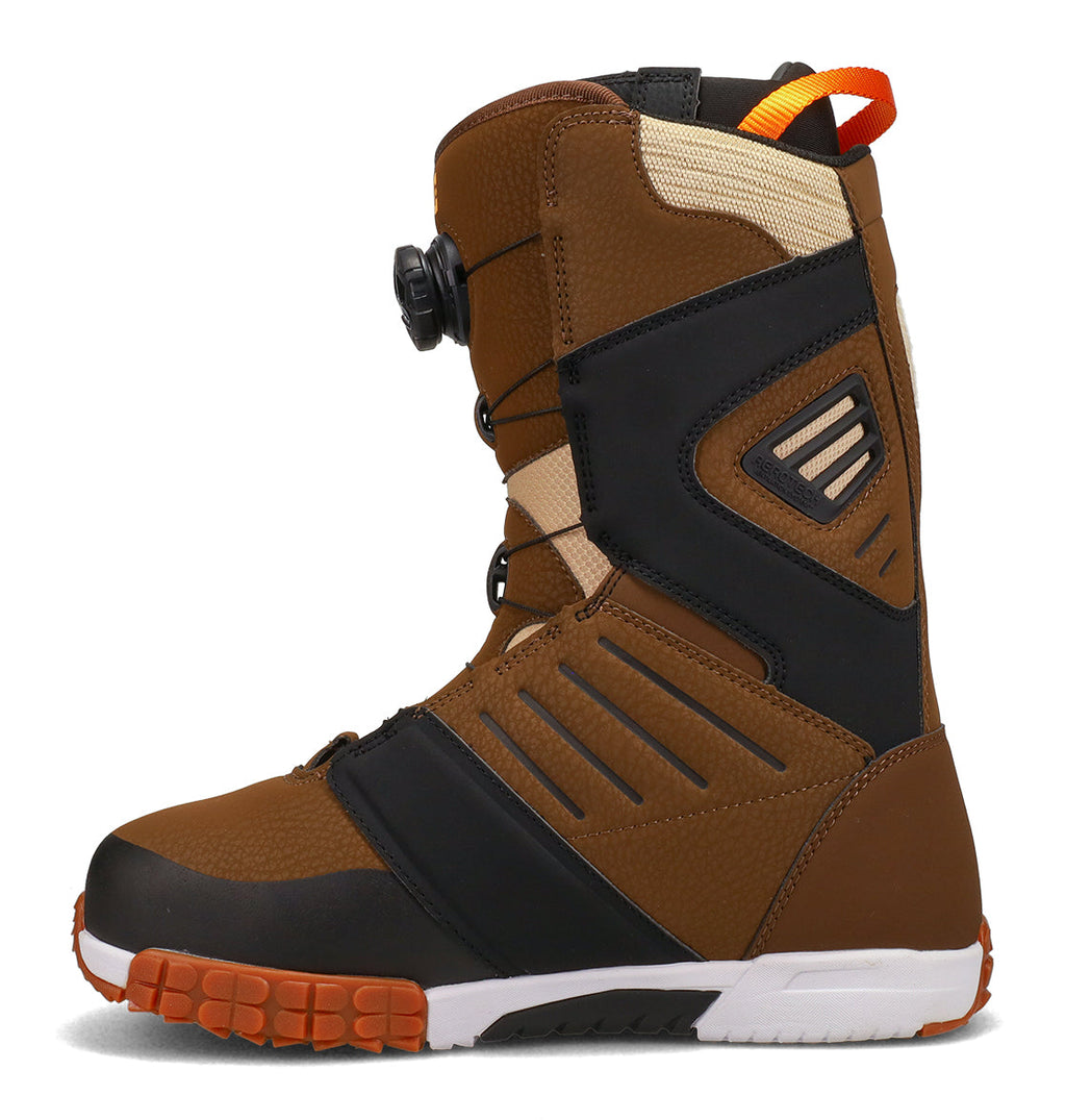 The DC Shoes Men’s Judge Snowboard Boots are shown from the side on a white background. These boots feature brown and black panels with orange and beige accents, a black dial closure system for advanced support, a durable rugged sole, and a pull loop at the back.