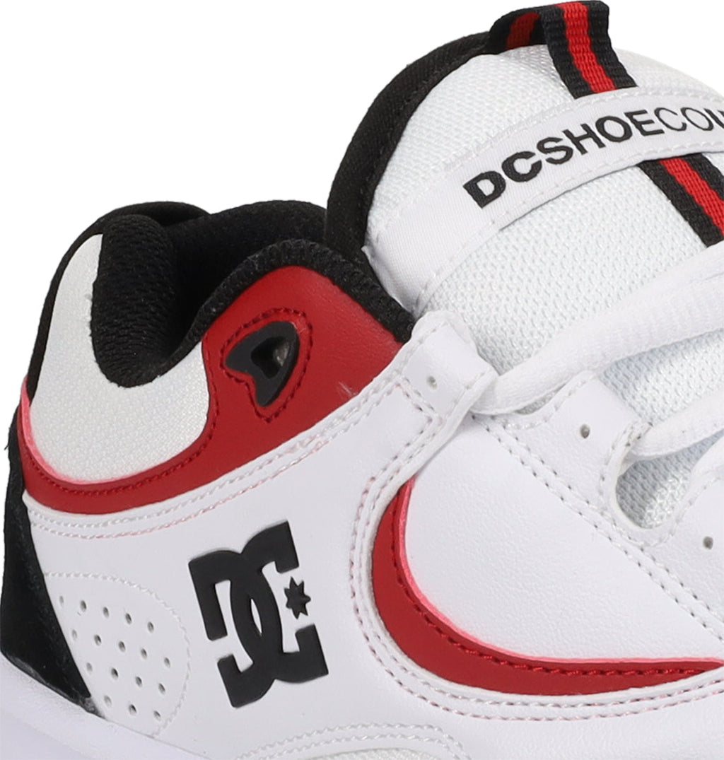 A close-up of the Men’s Kalynx Zero Shoes by DC Shoes in white, featuring red and black accents, highlights the iconic DC logo, detailed lace holes, and part of the tongue with DCSHOECO text—this model seamlessly combines style and performance for every skater.