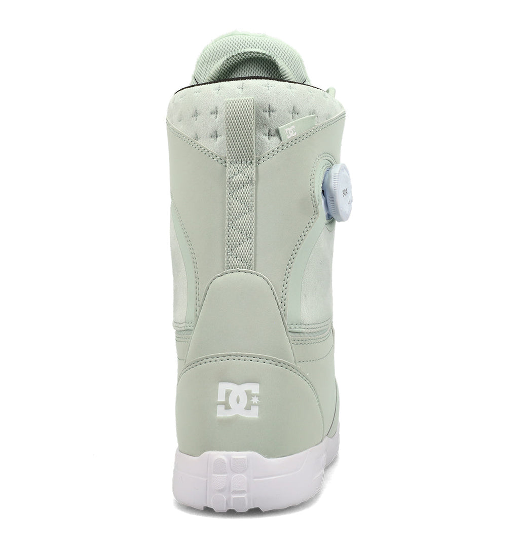 A light green DC Shoes Women’s Lotus Snowboard Boot viewed from the back, featuring a white logo near the heel and a side dial closure system. Designed for comfort and support, its sole and collar are finished in crisp white.