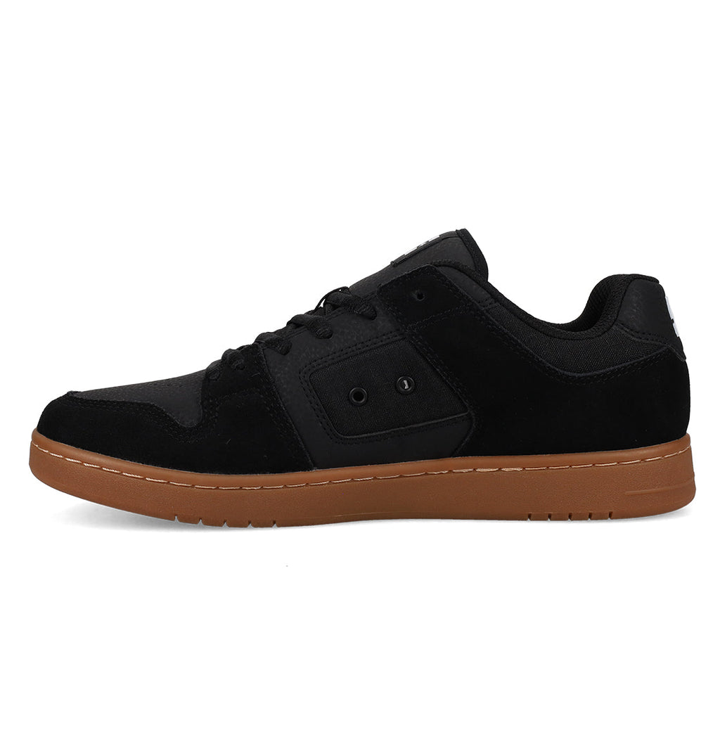 A side-view image of the DC Shoes Men’s Manteca 4 showcases a black low-top sneaker inspired by classic skate shoes, with a brown rubber sole, black laces, and understated stitching details set against a white background. Merging timeless design with modern comfort, this everyday style pays homage to the iconic DC Manteca collection.