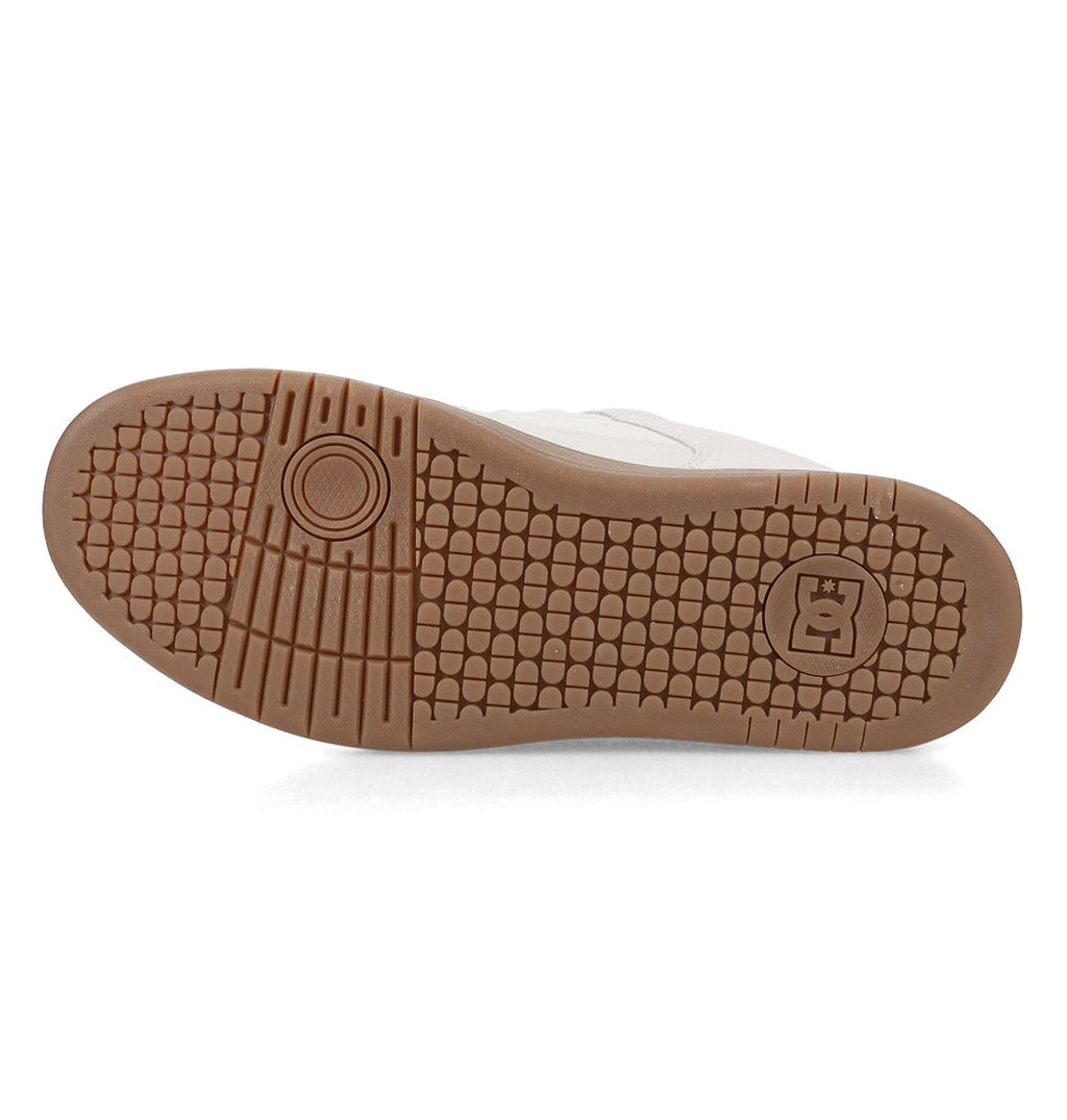 The image shows the brown rubber sole of the Men’s Manteca 4 Shoe by DC Shoes, featuring a textured tread pattern, circular detailing, and a crown-accented logo near the heel that highlights Manteca’s performance-driven design.