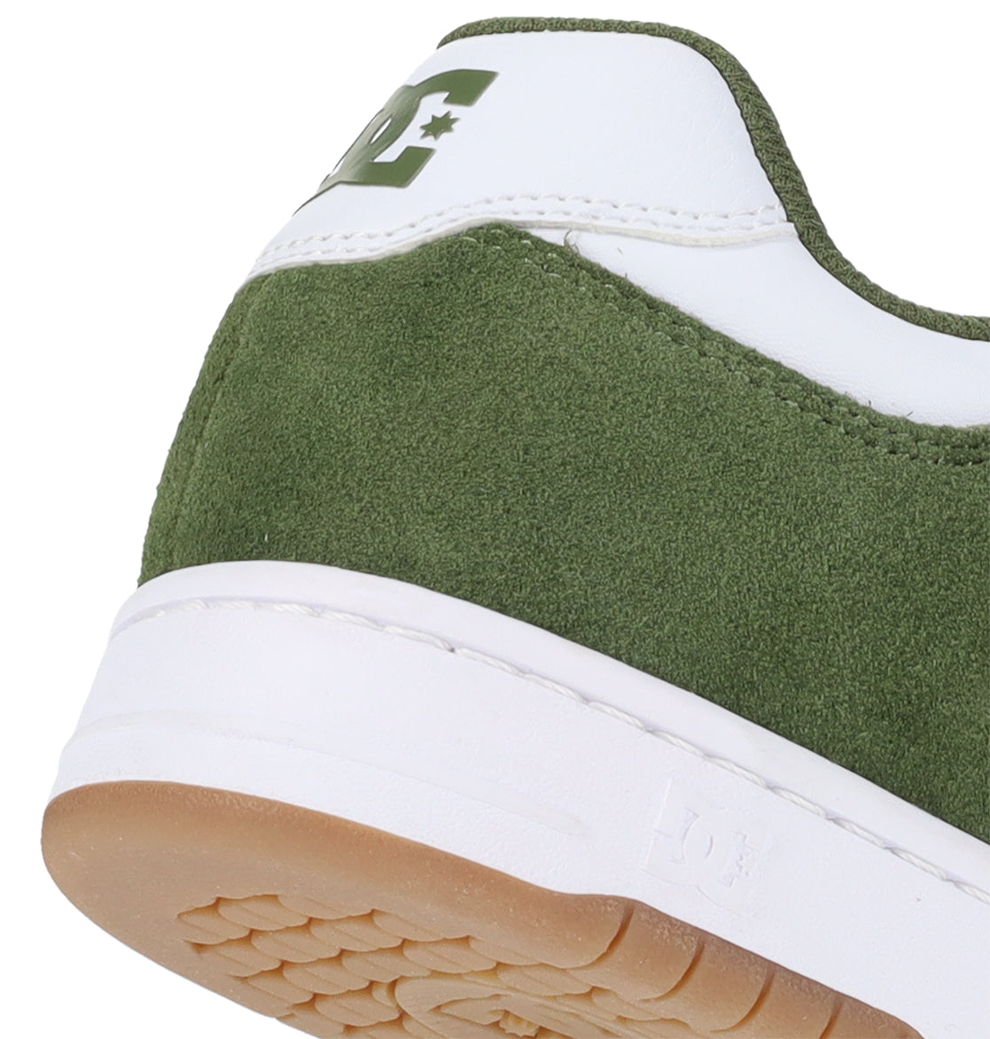 Close-up of the heel of a DC Shoes Men’s Manteca 4, showcasing green suede and white leather details, a white rubber sole, and a partial DC logo on the back—illustrating the performance-driven design typical of premium skate footwear.