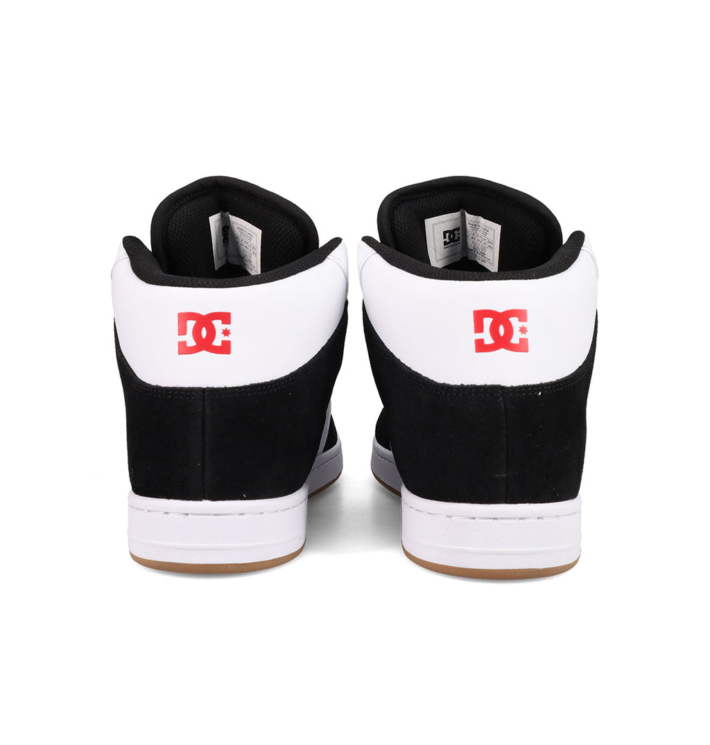 A pair of Men's Manteca 4 Hi Shoes by DC Shoes in black and white, seen from the back with a red DC logo on each heel and vintage high-top basketball-inspired details.