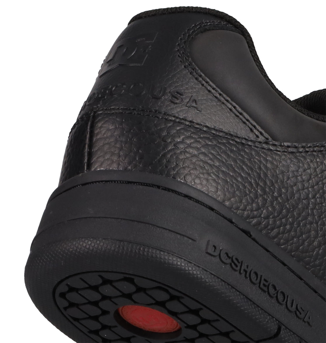 Close-up of the heel and sole of a black Men’s Manteca 4 SE Shoe by DC Shoes, showcasing textured leather, embossed DCSHOECOUSA branding, and a black rubber outsole with a red circular detail—all emphasizing its performance-oriented design.
