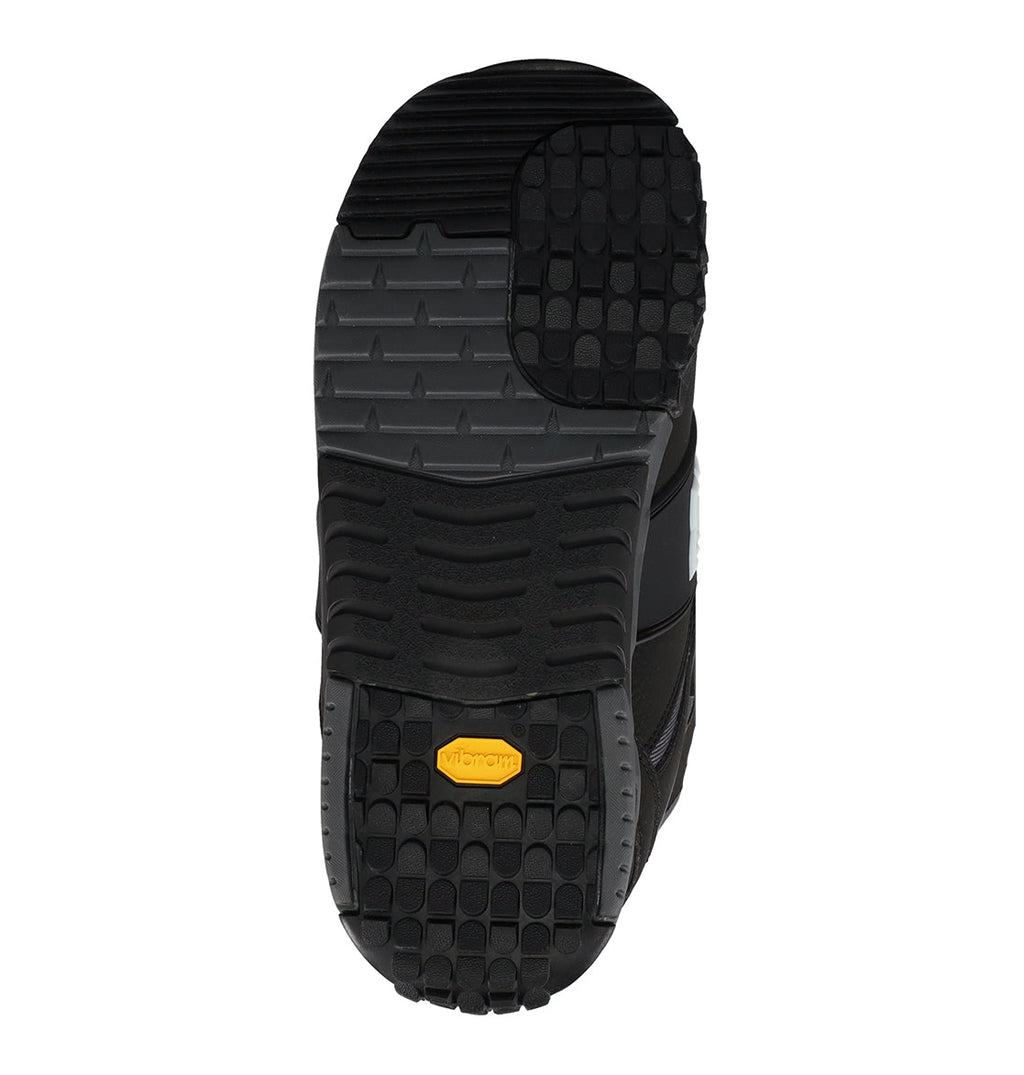 The image shows the black rubber sole of the Men’s Phantom Snowboard Boots by DC Shoes, featuring varied tread patterns and a small yellow Vibram logo near the heel, photographed on a white background. Designed for winter adventure, this rugged Vibram sole offers excellent grip and durability, making it ideal for challenging snowboarding conditions.