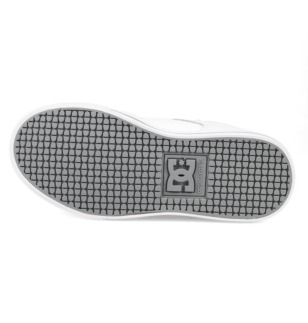 The image shows the sole of a white Kids’ Pure Shoe by DC Shoes, featuring a black patterned tread and the embossed DC logo near the center, highlighting its durable design.