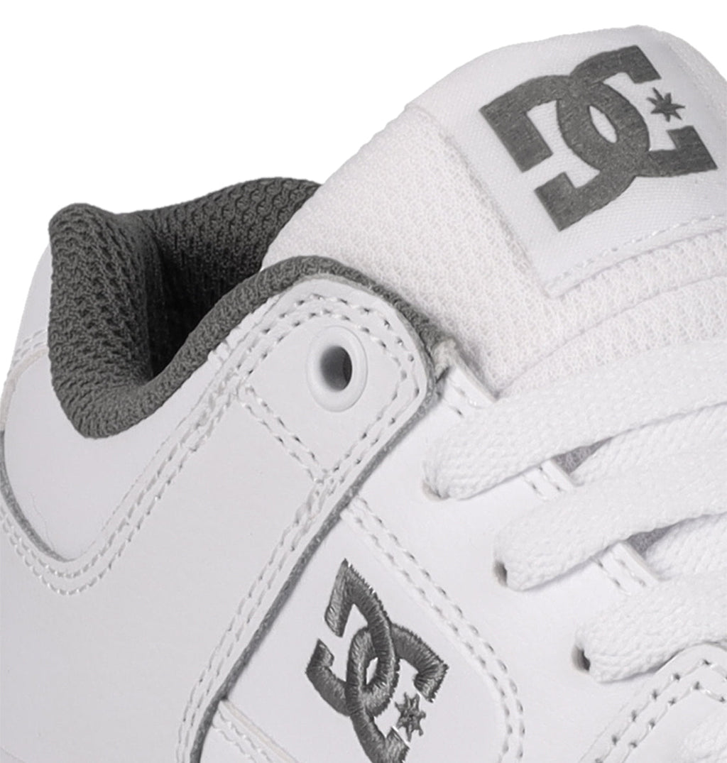 Close-up of a durable white DC Shoes Kids’ Pure Shoe, designed as a comfortable skate shoe for kids with gray logo accents, white laces, and a textured gray inner lining.
