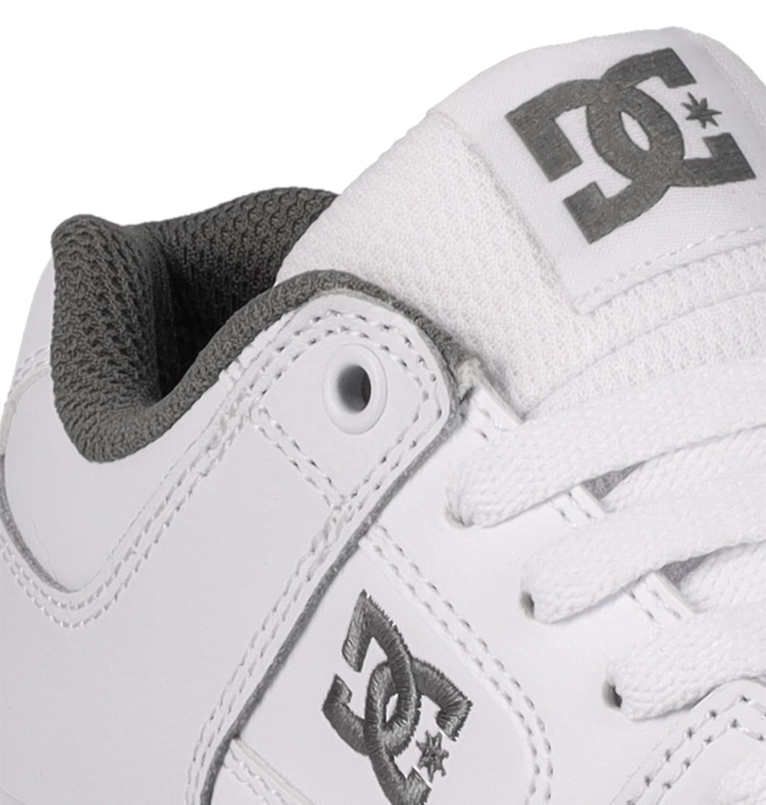 Close-up of a durable white DC Shoes Kids’ Pure Shoe, designed as a comfortable skate shoe for kids with gray logo accents, white laces, and a textured gray inner lining.