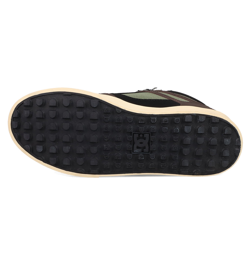 The image shows the bottom view of DC Shoes Men's Pure High Top WC Shoes with a black rubber sole, a grid of raised squares, the DC Shoes logo in the center, and a beige edge.
