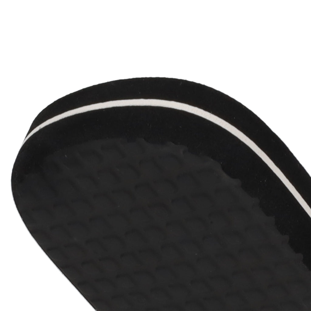 Close-up of the edge of a black Men’s Spray Slides sandal sole by DC Shoes, featuring a textured surface and a thin white stripe along the side, shown against a white background—these slides are an essential pick for comfort and style whether you’re relaxing after skating or heading out for the day.