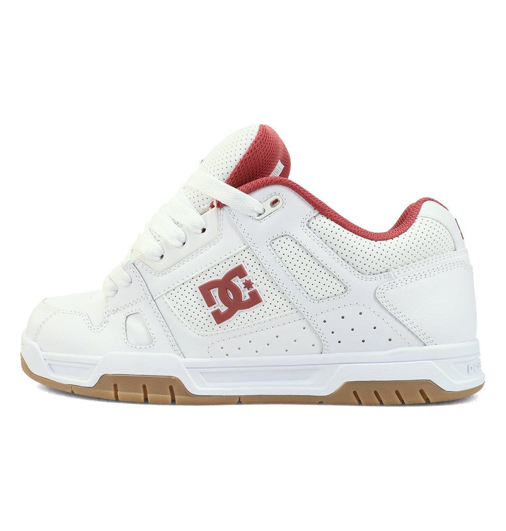 The DC Shoes Men’s Stag Shoe in white and red features a gum sole, a red DC logo on the side, an oversized puff tongue, and a comfortable red mesh lining—constructed with a durable cupsole and shown from the left side.