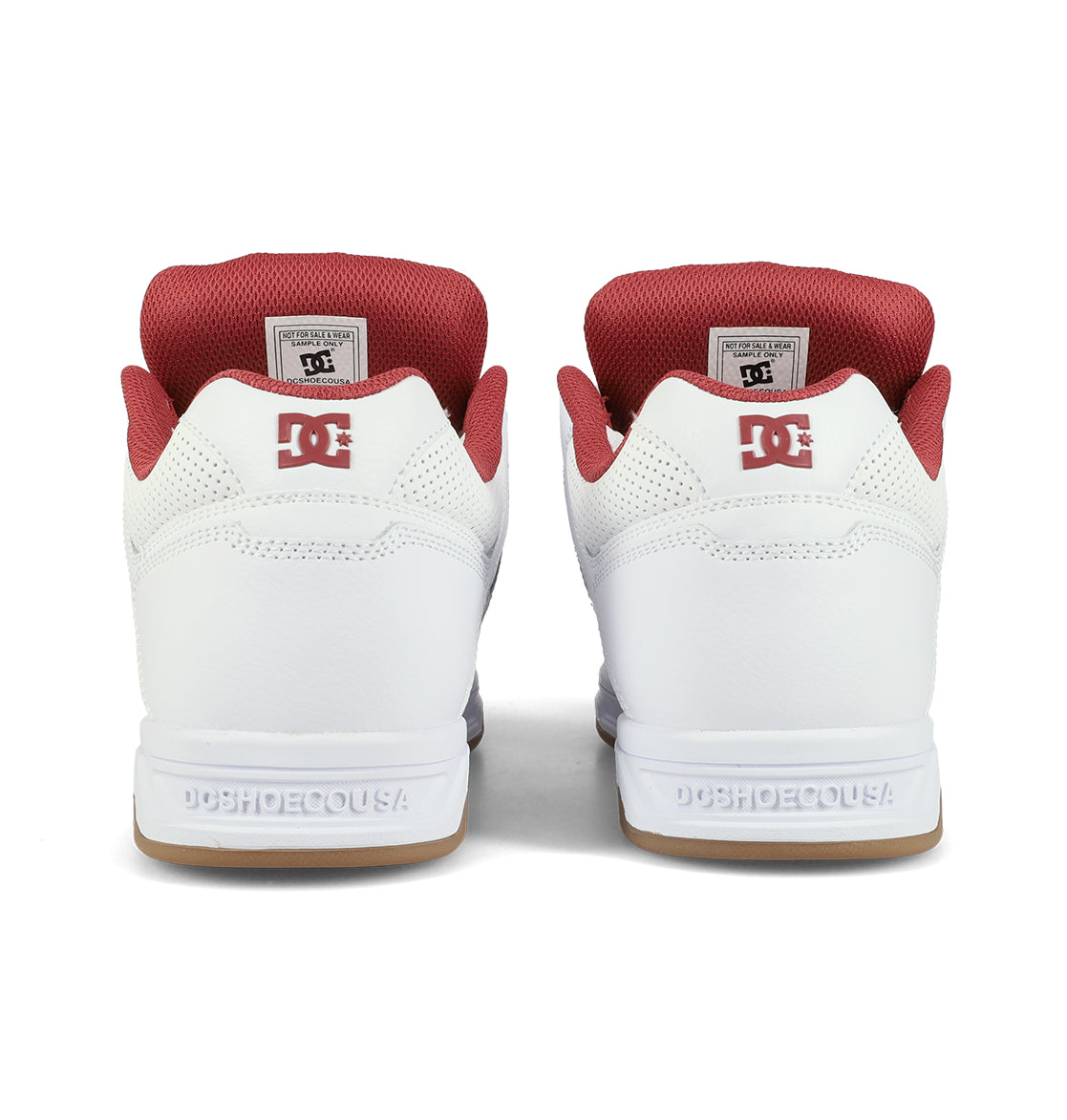 A pair of DC Shoes Men’s Stag Skate Shoes in white with red accents, seen from the back. These shoes feature an oversized padded collar for added comfort, signature DC logos on the heels, and “DCSHOECOUSA” embossed on their durable cupsole.