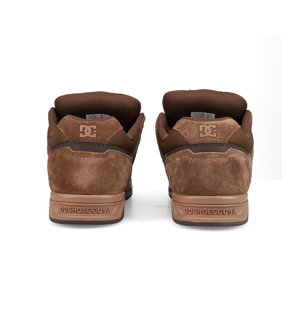 A rear view of the Men's Stag Shoes by DC Shoes, showcasing brown suede, cupsole construction, and DCSHOECOUSA embossed on the heels—a stylish nod to skate culture.