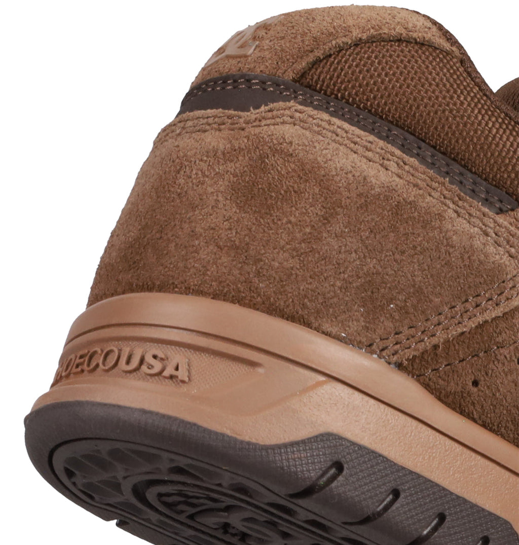 Close-up of the heel and sole of Men's Stag Shoes by DC Shoes in brown suede with dark brown trim, showing "DECOUSA" embossed on the rubber cupsole. The image highlights skate-inspired stitching, texture, and construction details.