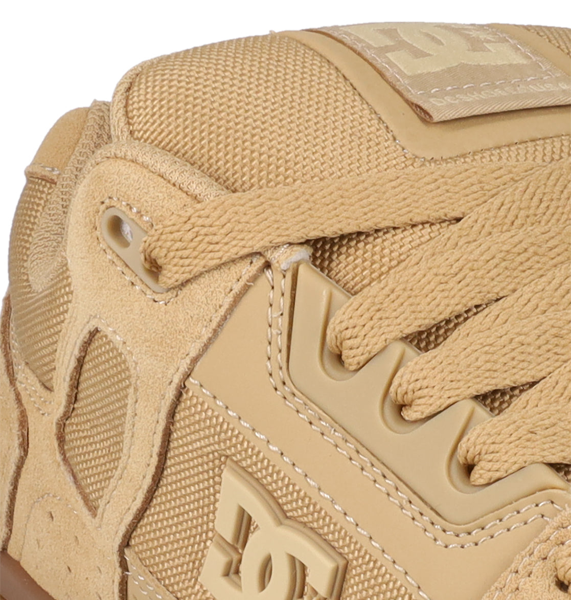 Close-up of the Men's Stag Shoes by DC Shoes, featuring tan suede and mesh uppers, thick laces, a prominent raised DC logo, and a durable cupsole—classic skate-inspired style and construction.