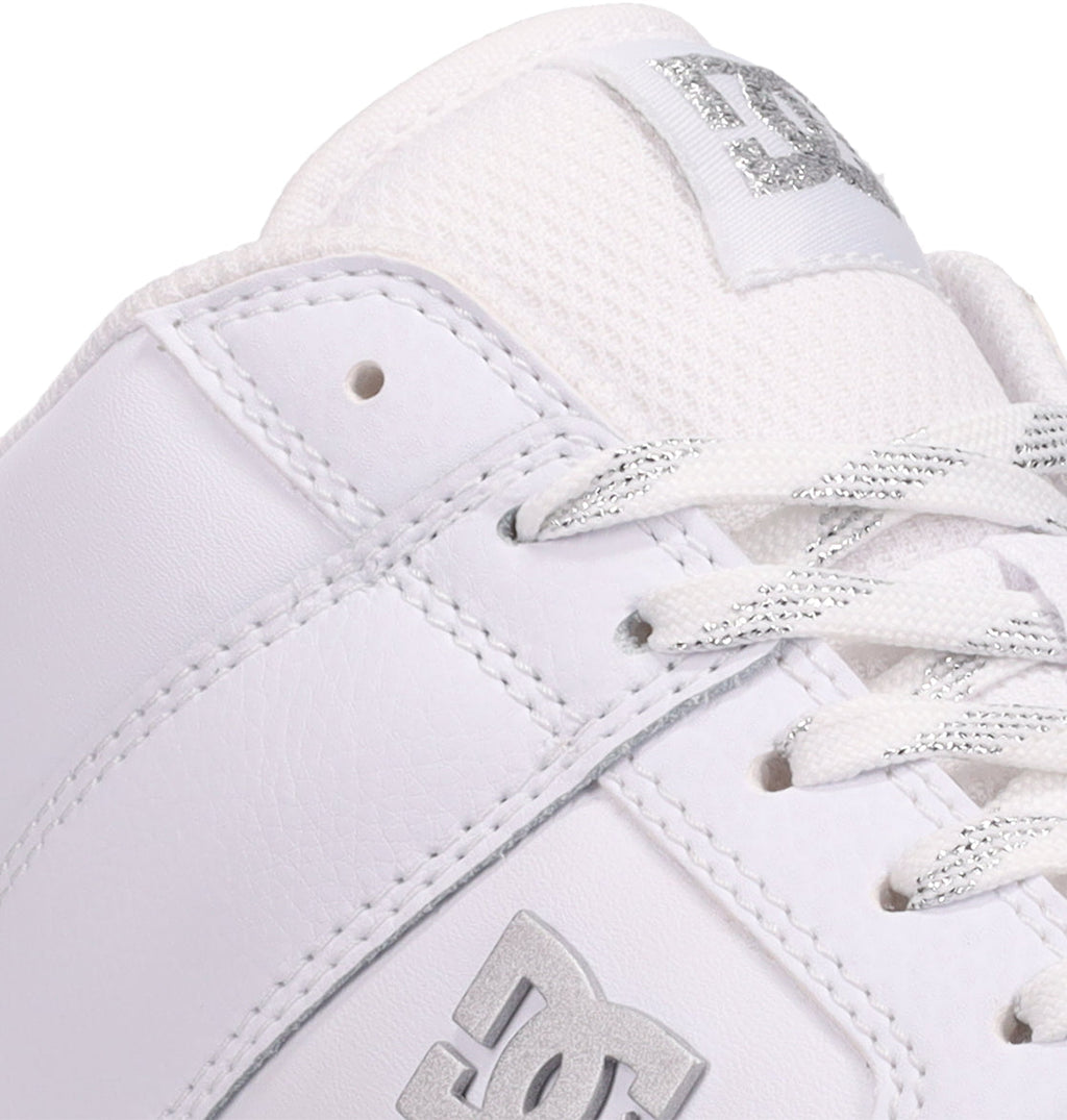 Close-up of the white DC Shoes Women’s Manteca 4 Hi High-Top Shoes featuring a silver DC logo on the side, white laces with silver accents, and visible stitching—showcasing its performance-inspired design.