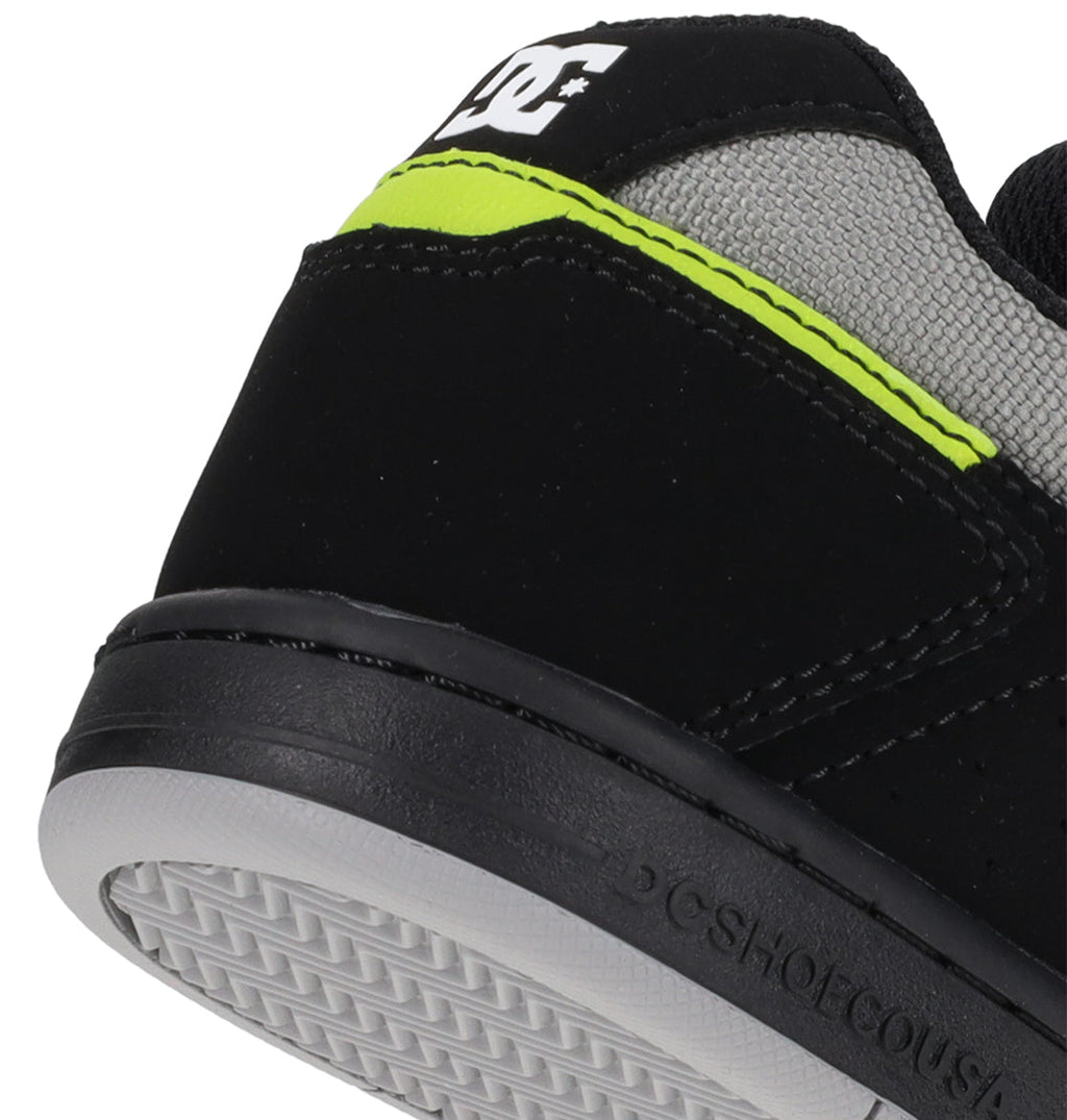Close-up of the heel of the Kids’ Stag Shoes by DC Shoes, featuring a black and gray design with a neon yellow stripe, white DC Shoes logo on the back, and textured rubber sole—this minimal silhouette is crafted as your everyday go-to vulcanized sneaker.