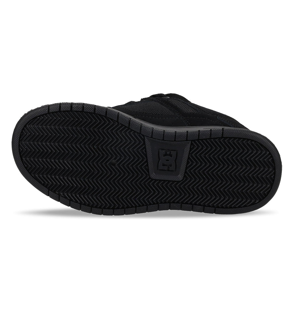 The image shows the black rubber sole of the Kids’ Stag Shoes by DC Shoes, featuring a herringbone tread pattern and a raised DC Shoes logo in the center, highlighting its durable cupsole construction.