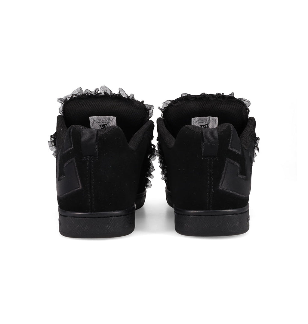 Back view of DC Shoes Women's Court Graffik SD shoes, featuring a black suede upper, frayed ankle details, black soles, and a textured black "E" design on the heel, placed side by side on a white background.