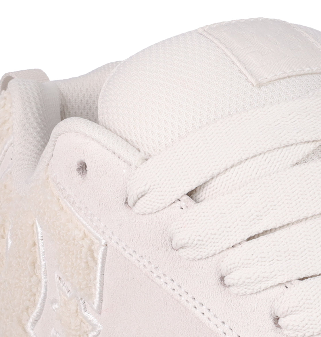 Close-up of DC Shoes Women's Court Graffik SD Shoes: white sneaker with textured fabric laces, suede upper with visible stitching, soft fleece-like accents, and a subtle embossed logo patch on the tongue—ideal for fans of on-trend styles.