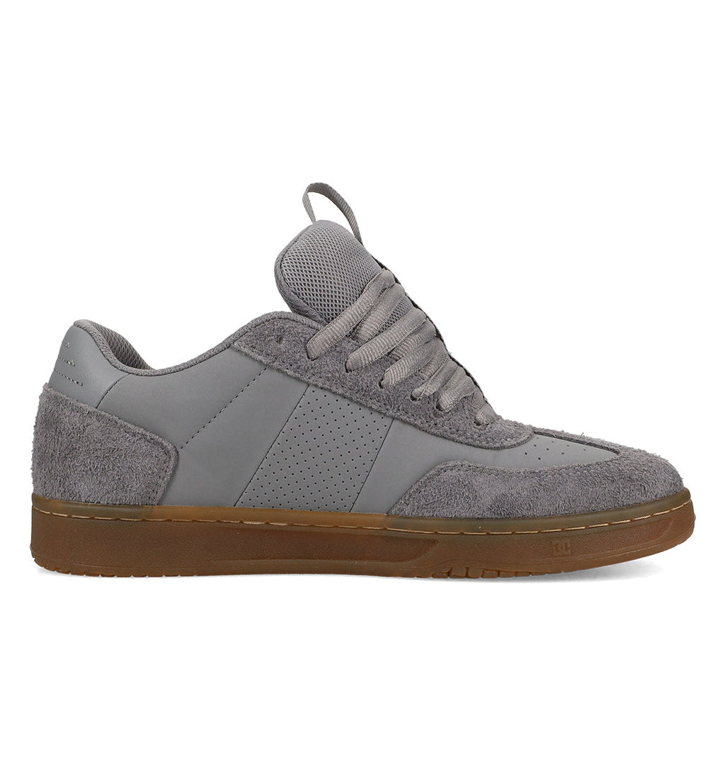 The DC Shoes Men’s Astrix Shoes are shown in a left side profile view against a white background, featuring a gray colorway with mixed suede and smooth textures, perforated side panel, thick laces, and a brown rubber sole. Designed for street skateboarding, they deliver enhanced board control with every step.